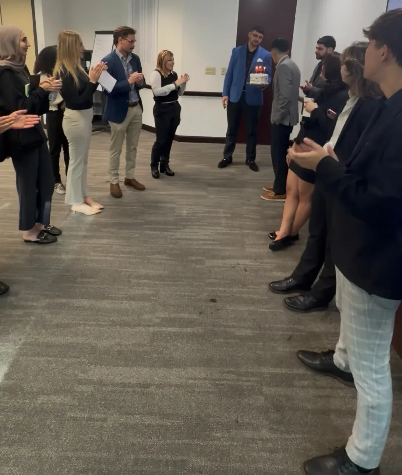 Employees applauding a teammate during an office celebration and recognition event.