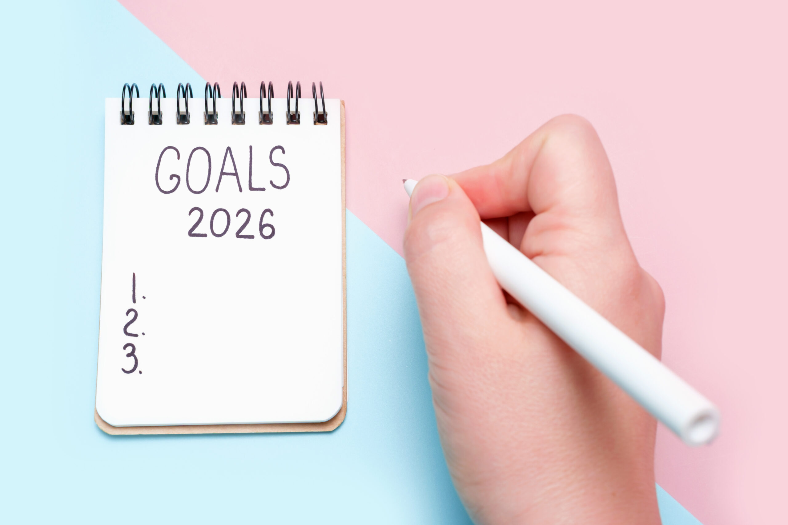 Hand writing goals in a notebook labeled “Goals 2026,” representing planning and personal development.